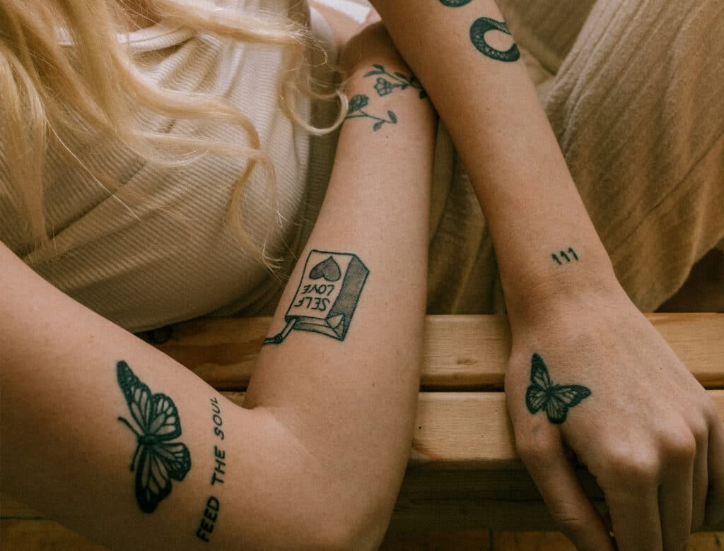 Tattovierte Frau die auf einem Stuhl sitzt. Schwanger was nun