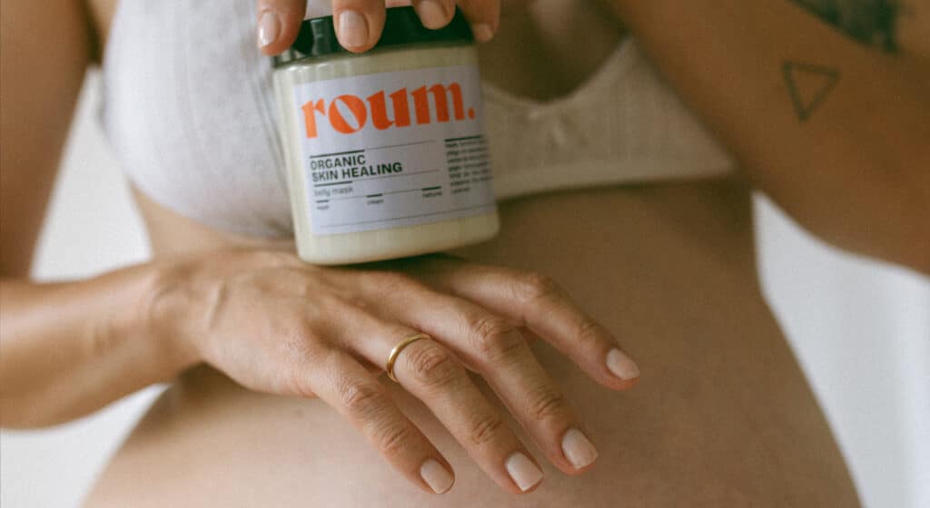 Frau hält eine roum skincare belly mask vor ihren schwangeren Bauch in den händen