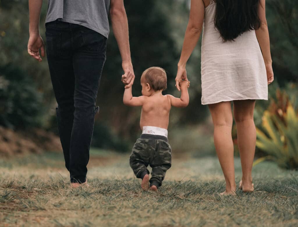 Elter nSpazieren mit ihrem kleinen Kind Hand in Hand in der Natur