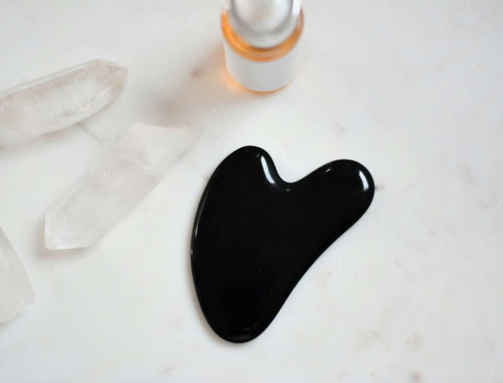 GUa Sha und Öl liegen auf einer Steinplatte